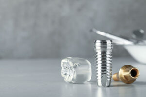 Dental implant pieces laying on a on a table, close up image of dental implant model. Reflecting off of the gloss table it shows all parts of a dental implants